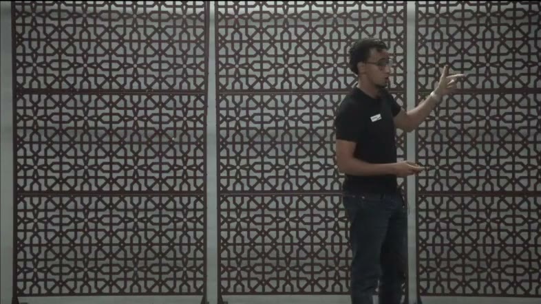 Oussama Hamouti stands in front of a lattice wall, gesturing as he talks through a sales playbook.
